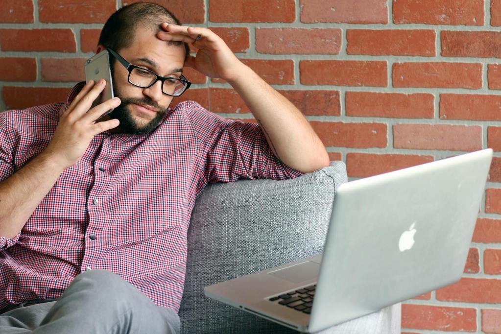 man sitting on sofa while talking on the phone